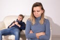 People, domestic violence and abuse concept - Woman with crossed arms and man on the white sofa Royalty Free Stock Photo