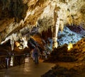 People dressed in white overalls exploring a huge cave of stalactites