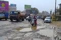 People driving on damaged road with potholes, Pune