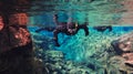 People snorkeling and diving in Blue crystal clear glacial water in Silfra Thingvellir national park Iceland