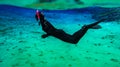 People snorkeling and diving in Blue crystal clear glacial water in Silfra Thingvellir national park Iceland