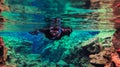 People snorkeling and diving in Blue crystal clear glacial water in Silfra Thingvellir national park Iceland