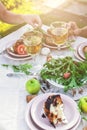 People eat at the table in the garden. Dinner at sunset with wine, grilled fish, fresh vegetables and herbs. Vertical shot