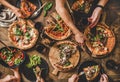 People eating different kinds of pizza, salad and drinking wine