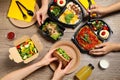 People eating healthy meals at wooden table. Food delivery
