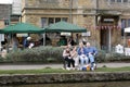 People eating lunch by The River Windrush in Bourton on the Water in Gloucestershire in the UK