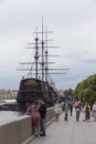 People on embankment. Dutch wooden fluyt merchant sailing ship of XVIII century with three masts