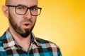 People and emotions. A bearded man with glasses and a blue checked shirt asks something in a dissatisfied voice. Yellow background Royalty Free Stock Photo