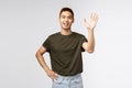 People, emotions and lifestyle concept. Portrait of friendly cheerful asian man saying hi, welcome person as waving hand Royalty Free Stock Photo