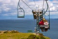 People and an empty chair on the cable chairlift to Alum Bay at the Needles landmark, Isle of White on a sunny day