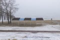 People on an empty spring beach by the river, trees and shelter from the sun. Foggy Royalty Free Stock Photo