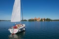 People enjoy boat trip at Galve lake with the Trakai castle at the background on a hot summer day in Trakai, Lithuania.