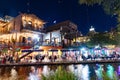 people enjoy the evening at the San Antonio River Walk with costumes by night and illuminated trees and restaurants