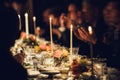 People enjoy a family dinner with candles. Big table served with food and beverages