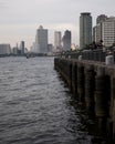 People enjoy a quiet time on a pier on the Chao Praya river in Bangkok, Thailand, with modern buildings in the background