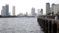 People enjoy a quiet time on a pier on the Chao Praya river in Bangkok, Thailand, with modern buildings in the background