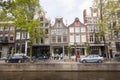 people enjoy spring sunshine in front of canal houses in amsterdam