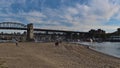 People enjoying the afternoon at Sunset Beach in Vancouver on the shore of False Creek with Burrard Street Bridge in background. Royalty Free Stock Photo