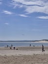 People enjoying the Beach at Beadnell Bay, with People walking along the Beach, Kite Surfers and Kayakers doing their Sports.