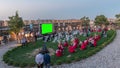 People are enjoying the open air cinema in the hictoric building at evening timelapse