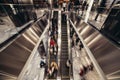 People on an escalator moving in the shopping mall to buy stuff in retail stores.