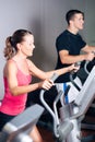 People exercising on elliptical trainer in gym