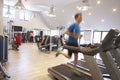 People exercising in a gym, blurred man runs in foreground Royalty Free Stock Photo