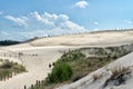 People explore in Lacka dune in Slowinski National Park in Poland. Traveling dune in sunny summer day. Sandy beach and blue sky