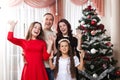 People family, christmas and adoption concept - happy mother, father and children hugging near a Christmas tree at home Royalty Free Stock Photo