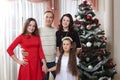 People family, christmas and adoption concept - happy mother, father and children hugging near a Christmas tree at home