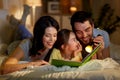 Happy family reading book in bed at night at home Royalty Free Stock Photo