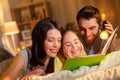 Happy family reading book in bed at night at home Royalty Free Stock Photo