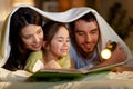 Happy family reading book in bed at night at home Royalty Free Stock Photo