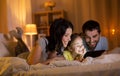 Family with tablet pc in bed at night at home