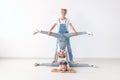 People, family and sport concept - young mom with twins daughters doing exercises on white background