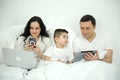 people, family and technology concept happy mother, father and little boy with tablet pc computer in bed at home or Royalty Free Stock Photo