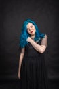 People and fashion concept - Woman with blue long hair dressed in black dress posing over black background Royalty Free Stock Photo