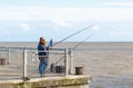 People fishing with fishing rods on Southwold Pier in the UK