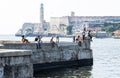 People fishing on sea wall in Havana Cuba with El Morro Castle in background