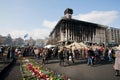 People with flowers walking past burnt building