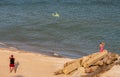 People fly a kite, by the sea