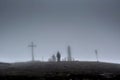 People in the fog near the huge cross and monument during raining day