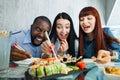 People, food, fun, sushi meal. Close up shot of excited hungry funny three multiethnical friends, having fun at cafe