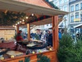 People fry grilled sausages on big hanging grill at Christmas market in Poznan