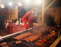 People fry grilled sausages on big hanging grill at Christmas market in Poznan Royalty Free Stock Photo