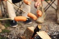 People frying sausages on bonfire outdoors