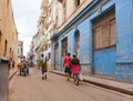 People going about their day in city street, one carrying large fish ion shoulder another on tricycle and two men walking away