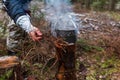 People are going to cook food in a pot on Swedish Fire Log. Burning a Swedish candle, torch in winter evening Royalty Free Stock Photo