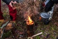 People are going to cook food in a pot on Swedish Fire Log. Burning a Swedish candle, torch in winter evening Royalty Free Stock Photo