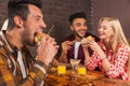 People Group Eating Fast Food Burgers Sitting At Wooden Table In Cafe Royalty Free Stock Photo